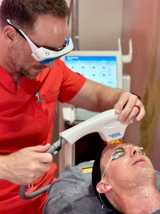 Provider performing a BBL® Hero broadband light therapy treatment on a client's face